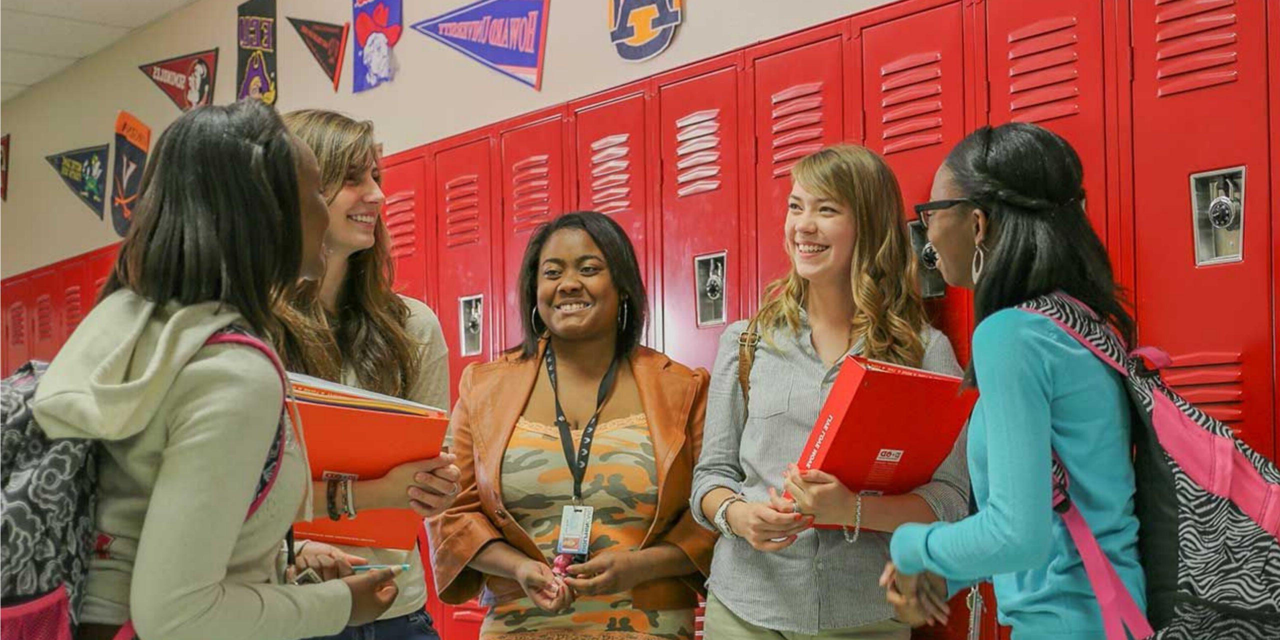高中学生在大厅红色储物柜前聊天